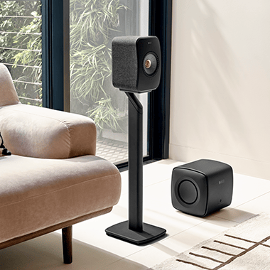 A pair of black LSX II speakers on a bookshelf.